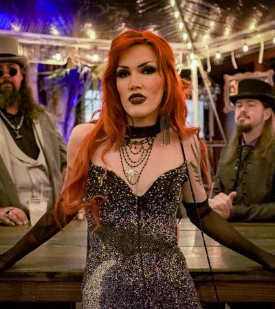 Three people in gothic steampunk attire posing indoors with dramatic lighting and dark vintage decor.