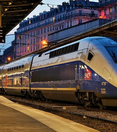 High-speed TGV train at a Paris station platform during twilight with city buildings in background