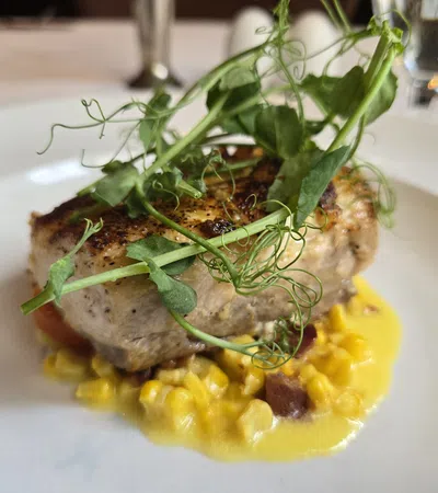 Grilled fish fillet topped with fresh pea shoots served on creamy corn sauce with bits of bacon.