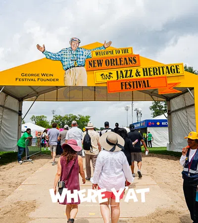 Entrance to the New Orleans Jazz and Heritage Festival with colorful signage and attendees.