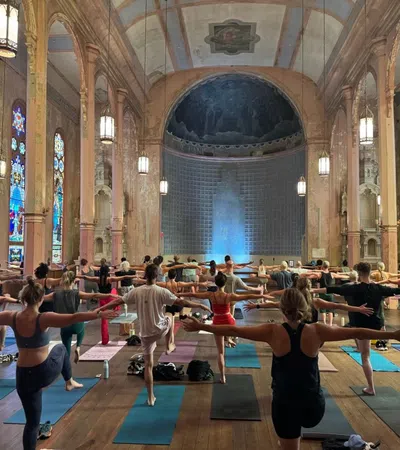 Group yoga session in a historic church with stained glass windows and wooden floors.
