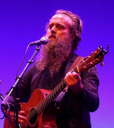 Iron & Wine playing a guitar on a stage