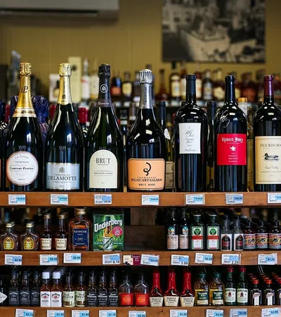 Variety of large champagne and wine bottles displayed on top of liquor shelves in a store