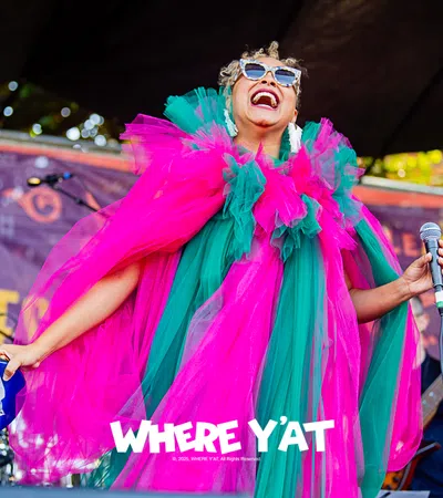 Colorful performer in vibrant costume singing on stage at a music festival.