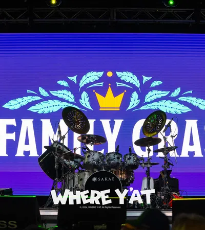a stage with a blue screen and a drum set and a crowd