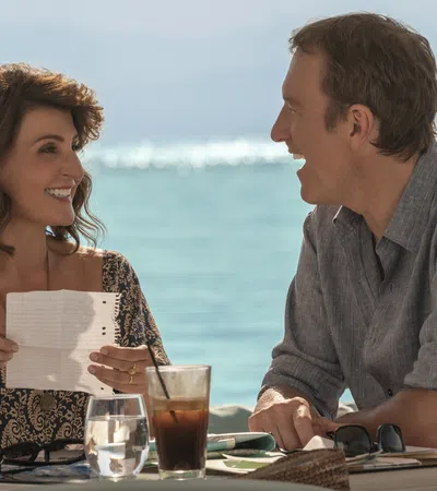 a man and a woman sitting at a table with drinks and papers