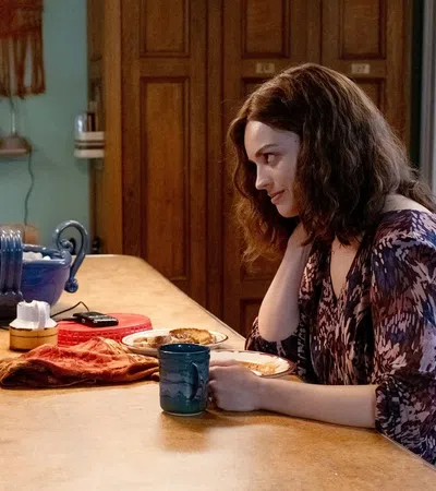 Two women sharing a warm conversation over coffee at a cozy kitchen table with plates and a large bowl.