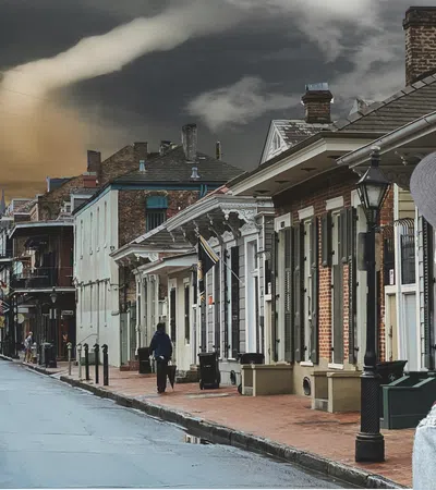 a person in a red coat on a street with buildings and a cloudy sky