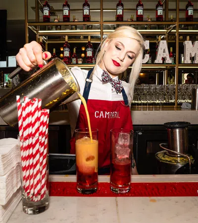 a person pouring a drink into a glass