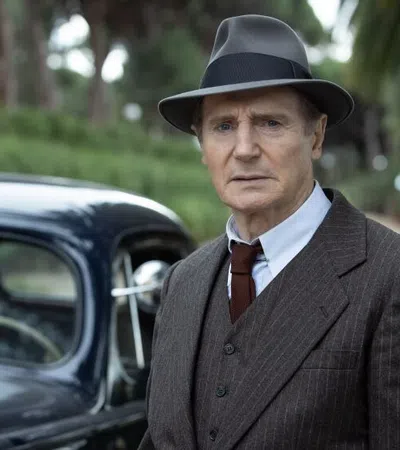 Liam Neeson in a suit and hat