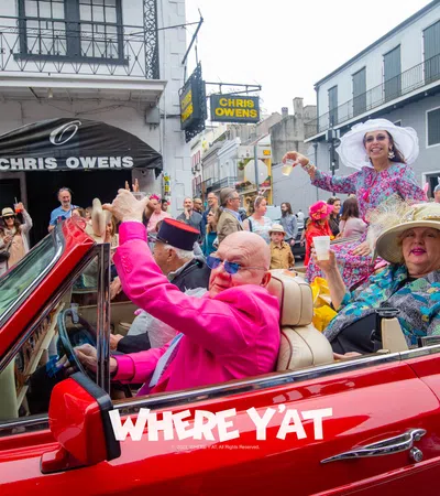 a group of people in a red car with a crowd watching