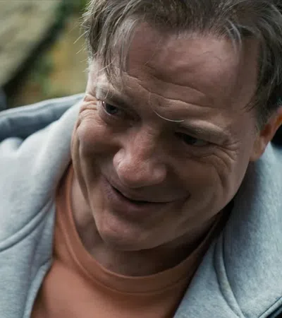 Middle-aged man smiling warmly at an elderly man in an outdoor setting with blurred natural background