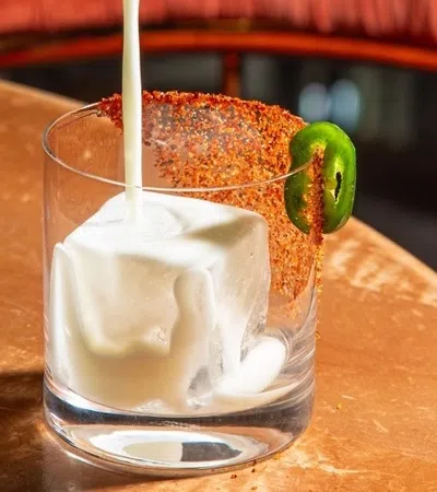 a person pouring a drink into a glass