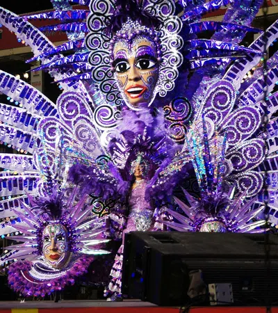 Vibrant carnival costume in purple with large feathered and sequined wings and detailed masks on stage.