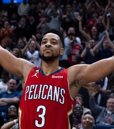 C.J. McCollum in a basketball uniform with his arms raised in front of a crowd