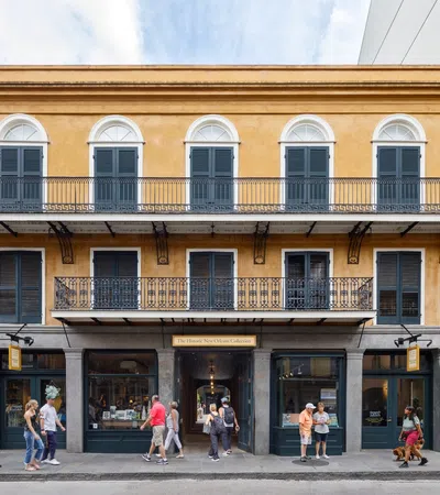 Historic two-story yellow building with arched windows and iron balconies, bustling with pedestrians on the street.