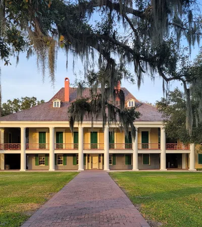a brick path leading to a house with Destrehan Plantation in the background