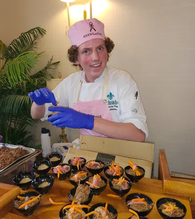 a person wearing a chef's outfit and gloves standing next to a table full of food