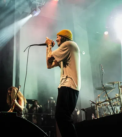 a man singing into a microphone on stage with a woman playing guitar