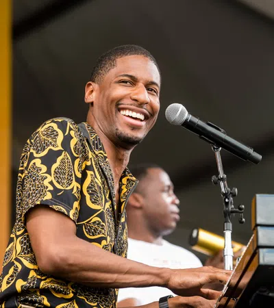 Smiling musician playing piano and singing into microphone during live outdoor performance