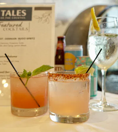 Three cocktails on a table with a menu in the background at Tales on the Crescent bar
