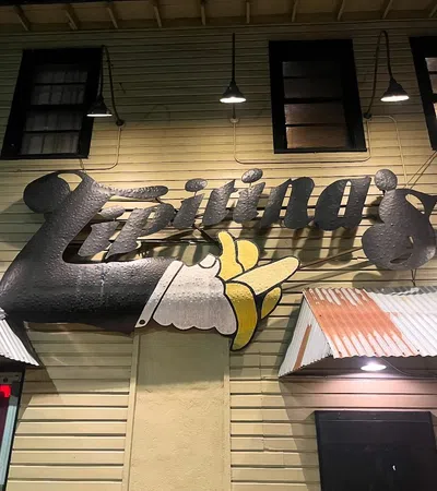 Sign for Lipiting's with a large pointing hand, mounted on a yellow wooden building under night lights.