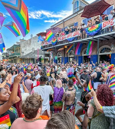 Crowd celebrating at a vibrant Pride parade with rainbow flags, colorful outfits, and lively street atmosphere.