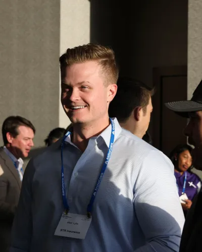 Group of professionals talking and networking at a business event in natural sunlight indoors.