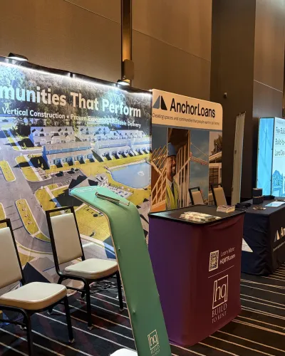 Trade show booths featuring Communities That Perform and AnchorLoans with promotional displays and seating.