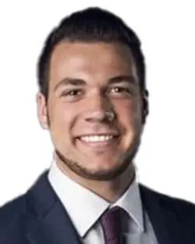 Smiling young man in a dark suit, white shirt, and maroon tie against a white background