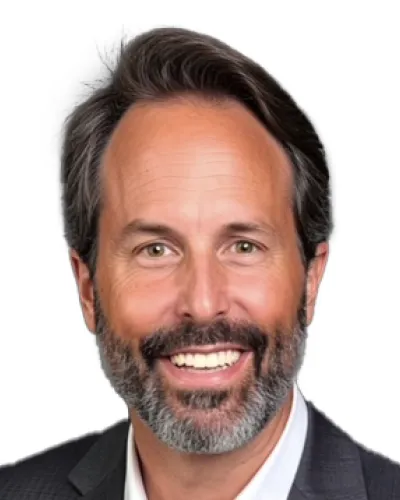 Smiling middle-aged man with gray beard wearing a dark gray suit and white shirt against white background