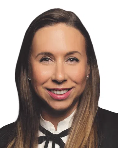 Smiling woman with long brown hair in business attire against a white background.