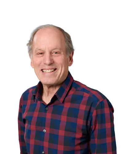 Smiling middle-aged man in a navy suit, white shirt, and striped tie against a white background