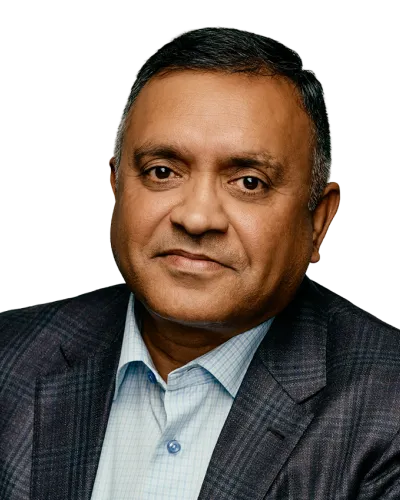 Middle-aged man wearing a dark plaid blazer and light blue checkered shirt against a black background.