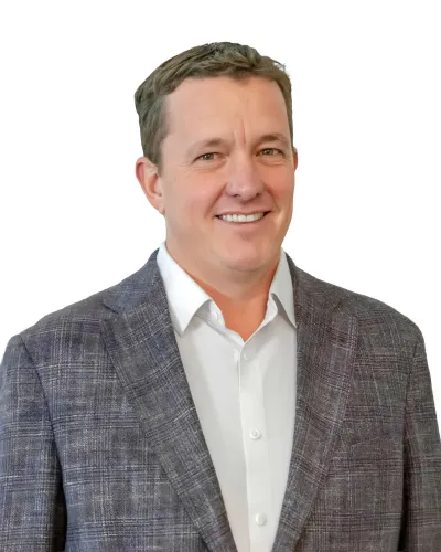Smiling man in a gray plaid blazer and white shirt on a white background, head and shoulders portrait.