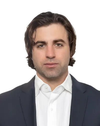 Professional man with medium-length brown hair wearing a navy suit jacket and white shirt against white background