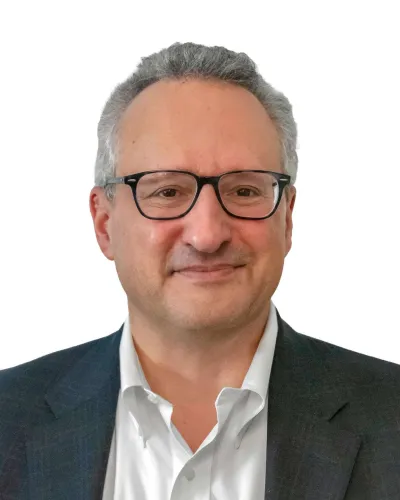 Professional middle-aged man wearing glasses and a suit smiling against a white background