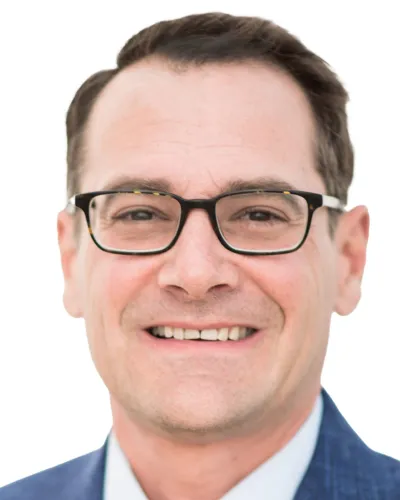 Smiling man wearing black glasses and a blue suit jacket on white background