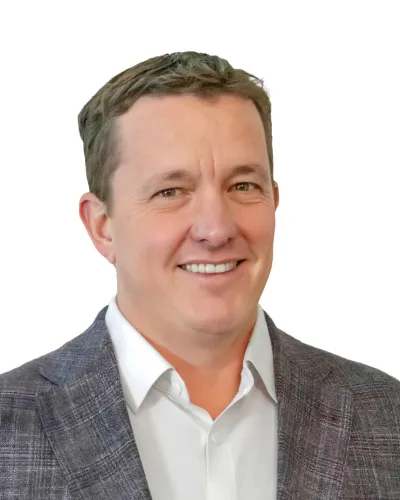 Smiling man in a gray plaid blazer and white shirt on a white background, head and shoulders portrait.