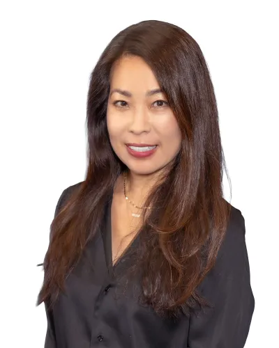 Smiling woman with long brown hair in a black blouse against white background.
