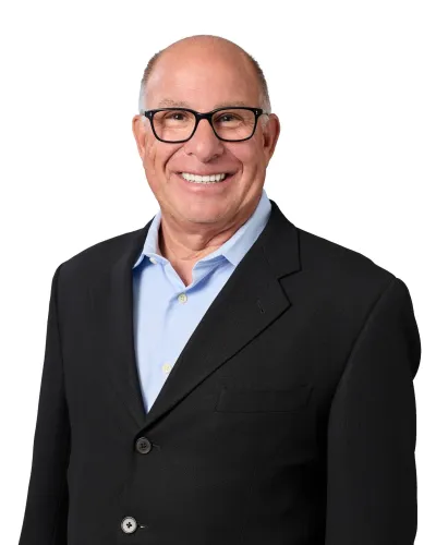 Smiling bald man wearing black glasses and a white shirt with a dark jacket against a white background