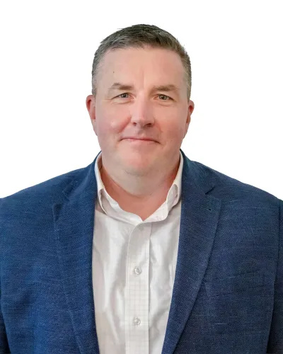 Professional middle-aged man wearing a white shirt and blue blazer smiling against white background