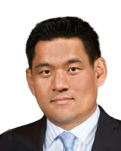 Professional headshot of a man in a suit with a light blue tie and white shirt on a white background