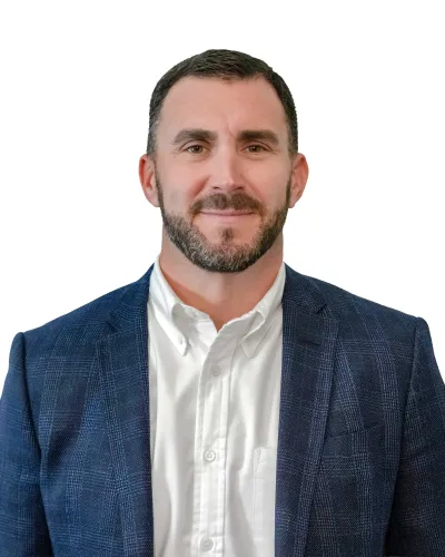 Professional man with short dark hair wearing a suit, light blue shirt, and patterned tie against white background