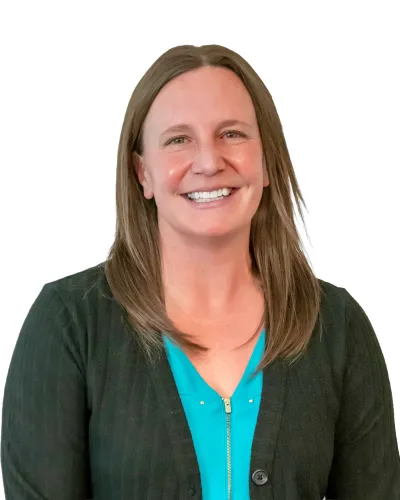 Smiling woman with straight brown hair wearing a black cardigan over a blue top against a white background