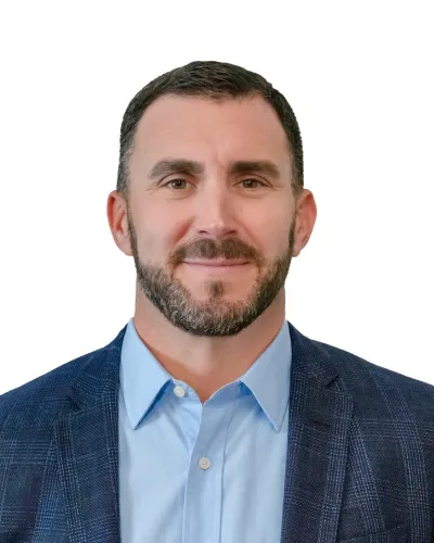 Professional man with short dark hair wearing a suit, light blue shirt, and patterned tie against white background