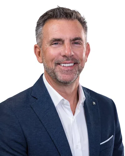 Smiling middle-aged man in a navy blazer and white shirt against a white background.