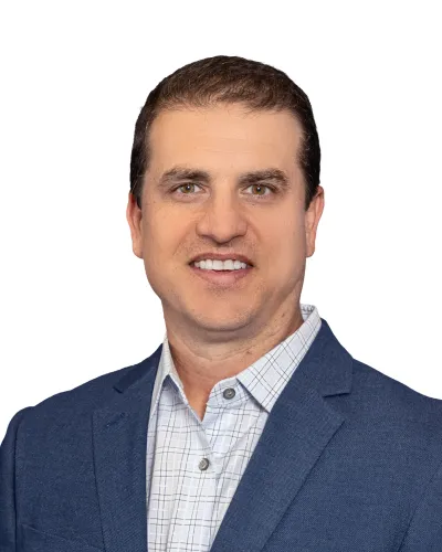 Smiling man in blue blazer and checkered shirt against white background headshot