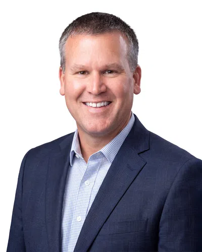 Smiling professional man in checkered shirt and navy blue blazer against white background