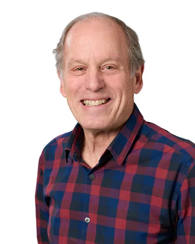 Smiling middle-aged man in a navy suit, white shirt, and striped tie against a white background